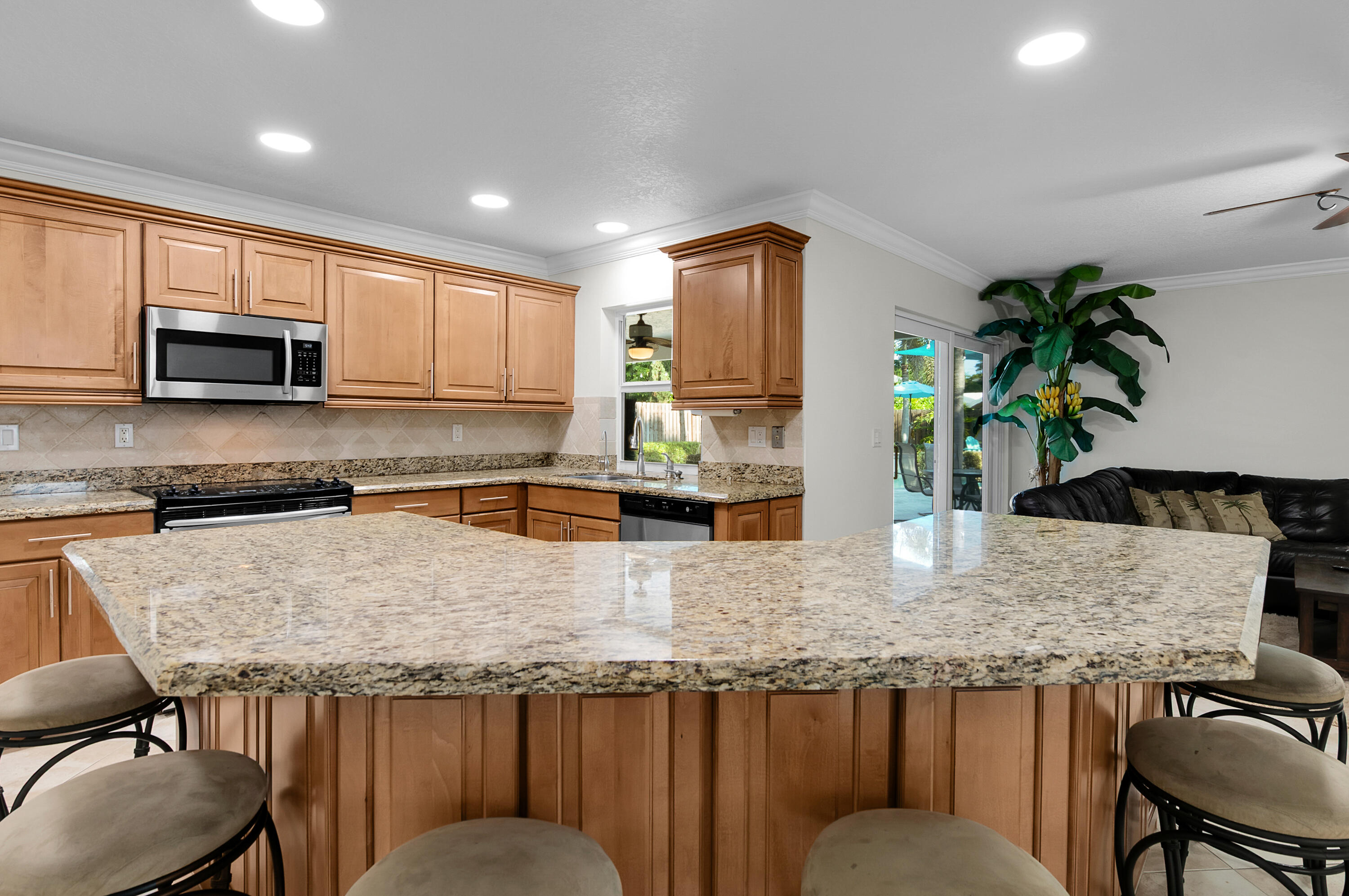 1560 Southwest 16th Street Boca Raton, FL 33486 - Photo 43 of 72 a kitchen with stainless steel appliances granite countertop a table chairs in it and wooden floors