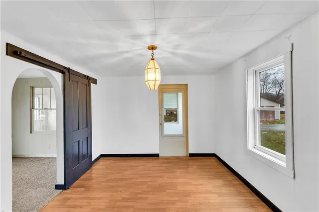 a view of an empty room with window and wooden floor