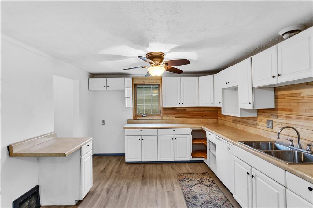 531 5th Avenue Avonmore, PA 15618 - Photo 10 of 25 a kitchen with a sink dishwasher a stove and white cabinets with wooden floor