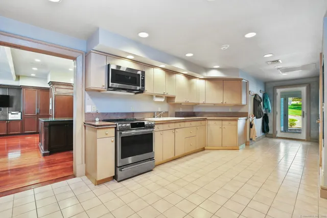 a large kitchen with stainless steel appliances kitchen island granite countertop a sink and cabinets