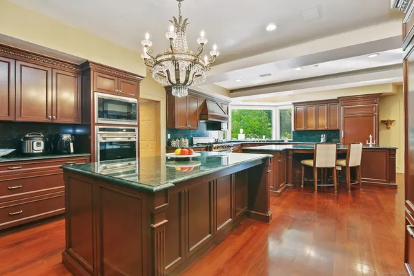 a kitchen with stainless steel appliances granite countertop table chairs and wooden cabinets