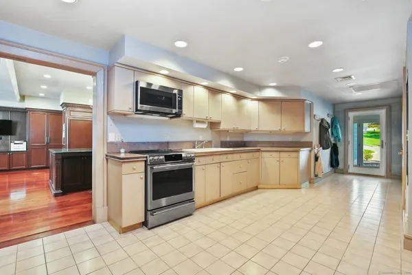 a large kitchen with stainless steel appliances kitchen island granite countertop a sink and cabinets