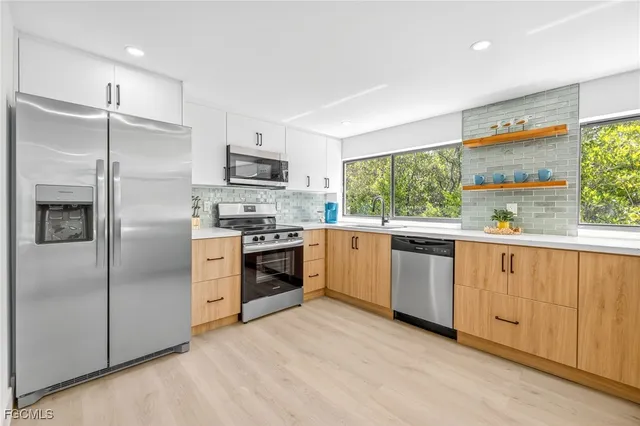 a kitchen with granite countertop stainless steel appliances a refrigerator cabinets and a window