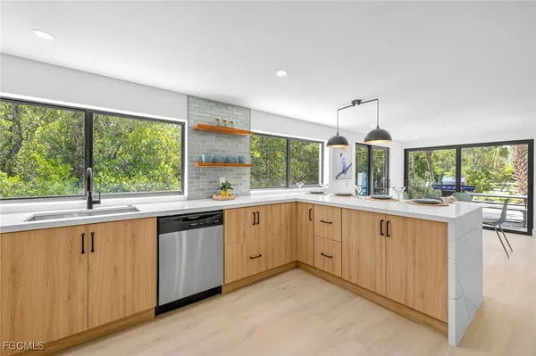 a large kitchen with kitchen island granite countertop a large window and white cabinets