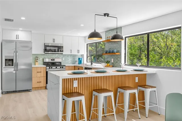 a kitchen with stainless steel appliances granite countertop a stove a refrigerator a kitchen island a sink and a refrigerator