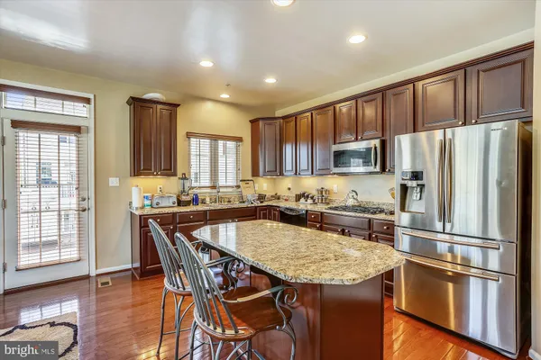 a kitchen with stainless steel appliances granite countertop a refrigerator a stove a sink a dining table and chairs