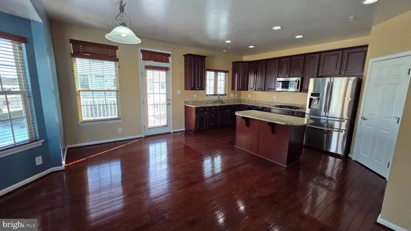 a kitchen with kitchen island wooden floor center island and stainless steel appliances