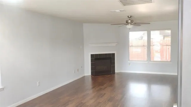 an empty room with wooden floor fireplace and windows