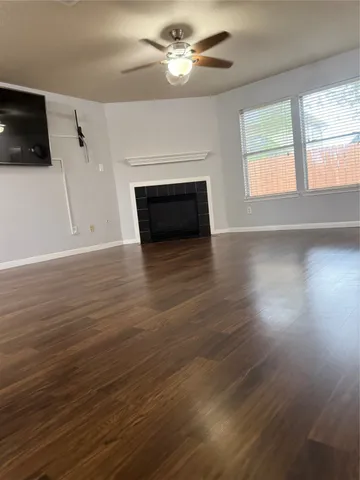 an empty room with wooden floor fireplace and windows