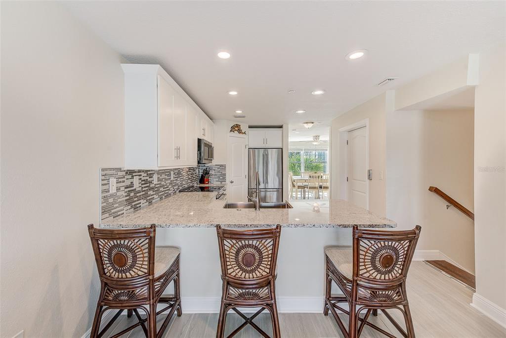 100 Windrush Boulevard, Unit 2 Indian Rocks Beach, FL 33785 - Photo 25 of 73 a kitchen with stainless steel appliances granite countertop a table and chairs