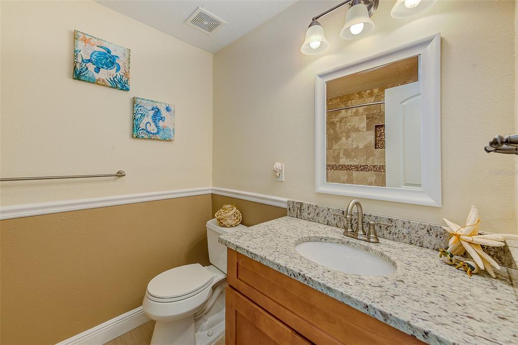 100 Windrush Boulevard, Unit 2 Indian Rocks Beach, FL 33785 - Photo 28 of 73 a bathroom with a granite countertop sink mirror vanity and toilet