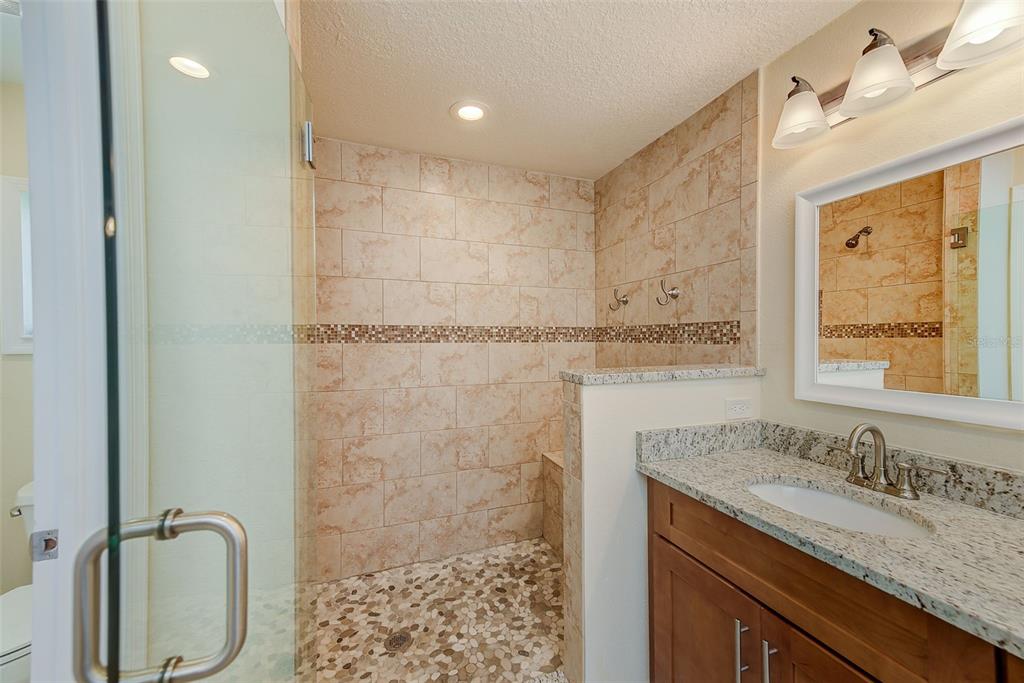 100 Windrush Boulevard, Unit 2 Indian Rocks Beach, FL 33785 - Photo 35 of 73 a bathroom with a granite countertop sink a mirror and a shower