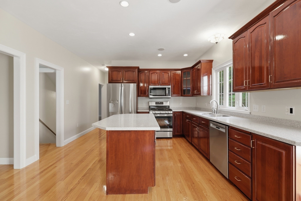 61 Indian Head Road Framingham, MA 01701 - Photo 8 of 42 a large kitchen with stainless steel appliances kitchen island granite countertop wooden cabinets a refrigerator and a sink