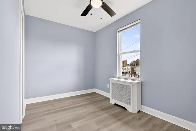 an empty room with wooden floor cabinet and windows