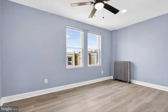 a view of an empty room with a window and wooden floor
