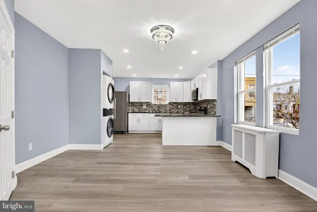 a large kitchen with kitchen island a stove a refrigerator and white cabinets with wooden floor