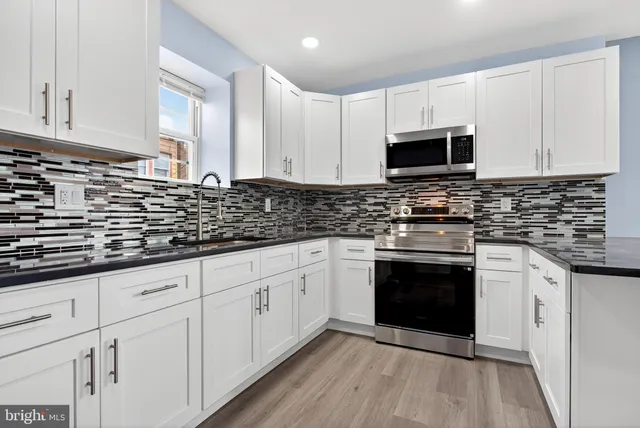 a kitchen with stainless steel appliances granite countertop a stove a sink and white cabinets