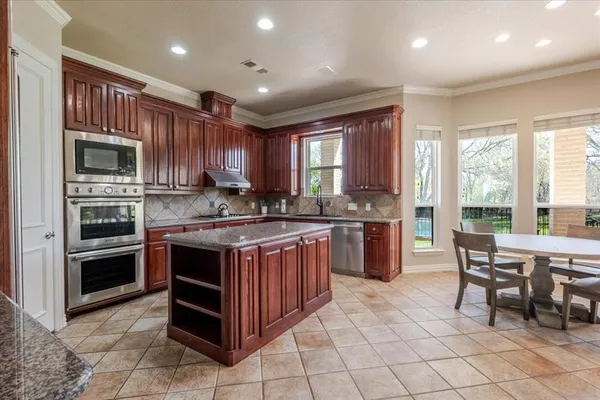 a kitchen with stainless steel appliances granite countertop a stove top oven a sink dishwasher a dining table and chairs with wooden floor