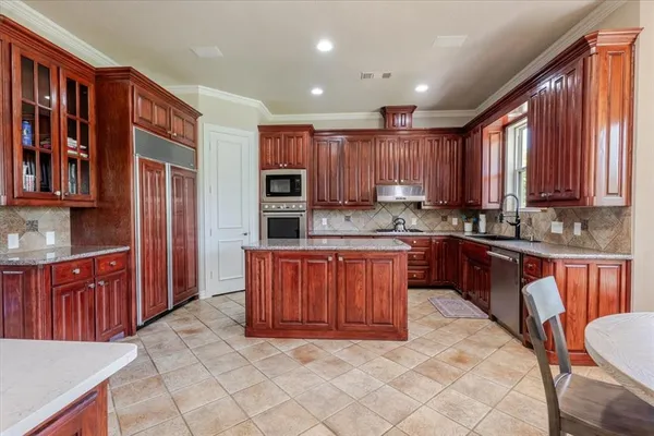 a large kitchen with stainless steel appliances granite countertop a stove sink and cabinets