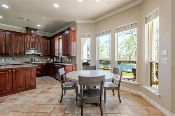 a kitchen with granite countertop a stove a sink a dining table and chairs