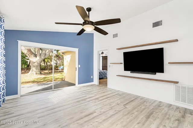 a view of a livingroom with wooden floor and a ceiling fan