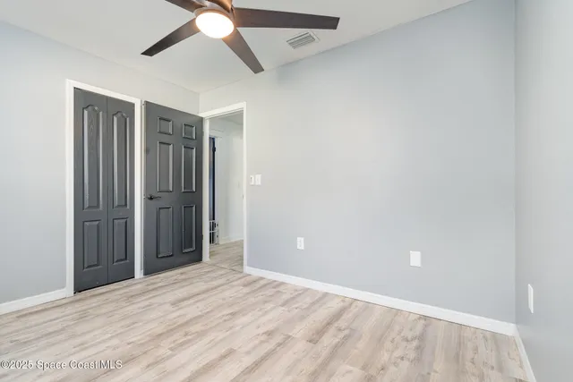 an empty room with closet and a chandelier fan