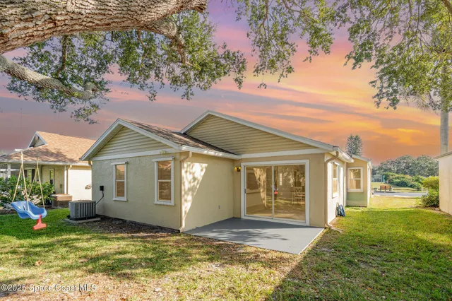 a view of a house with a big yard and potted plants and a large tree