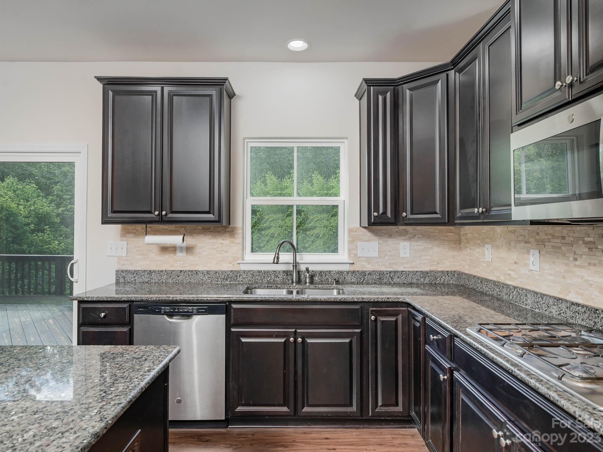 7524 West Berkeley Road Denver, NC 28037 - Photo 3 of 31 a kitchen with granite countertop a sink stove and cabinets