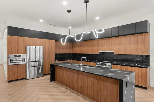 a kitchen with stainless steel appliances granite countertop a sink a stove and a refrigerator