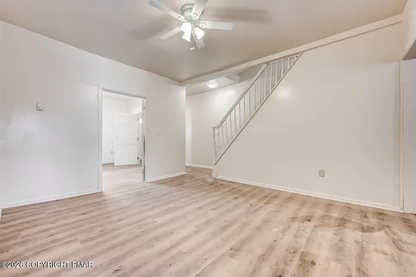 a view of an empty room with window and wooden floor