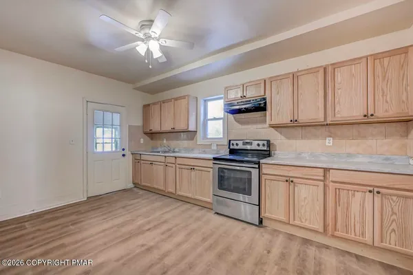 a large kitchen with granite countertop a stove top oven a sink dishwasher a refrigerator and white cabinets with wooden floor