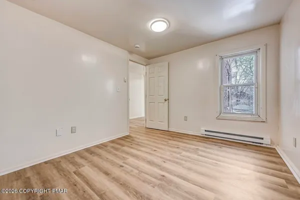 an empty room with wooden floor and windows