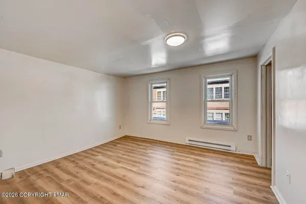 a view of an empty room with wooden floor and a window