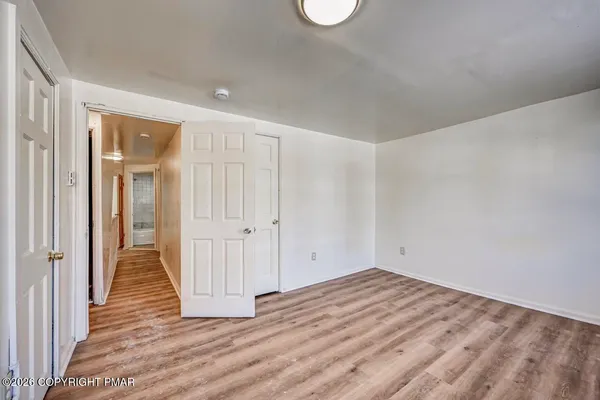 a view of an empty room with wooden floor and stairs