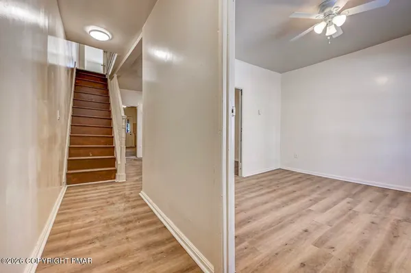 a view of empty room with wooden floor and fan