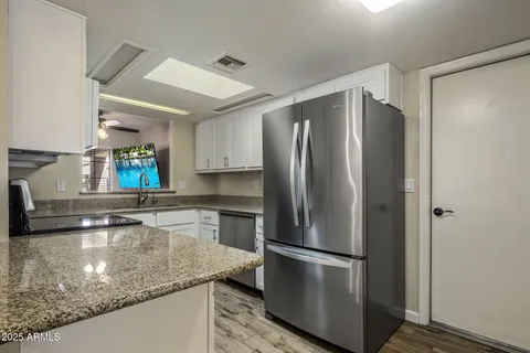 a kitchen with stainless steel appliances granite countertop a refrigerator a stove and a sink with wooden floor