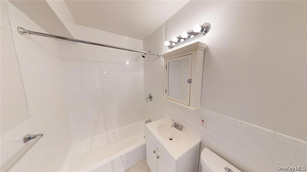 4200 Herkimer Place, Unit 4E Bronx, NY 10470 - Photo 2 of 8 Full bathroom featuring tub / shower combination, vanity, tile walls, and wainscoting