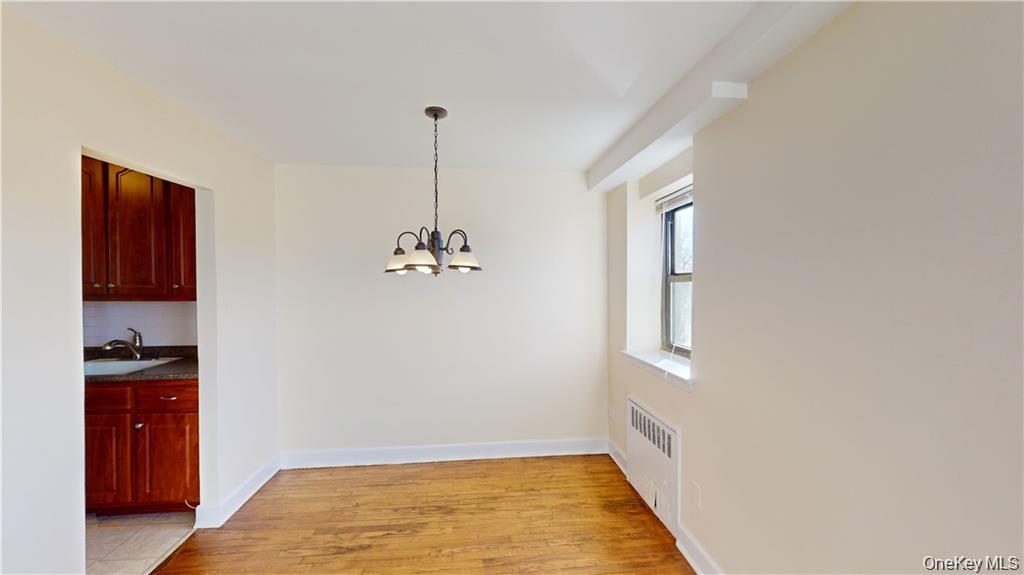 4200 Herkimer Place, Unit 4E Bronx, NY 10470 - Photo 5 of 8 Unfurnished dining area featuring radiator heating unit, light wood-style floors, and a chandelier