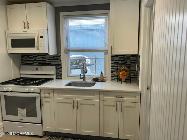 a kitchen with white cabinets and appliances