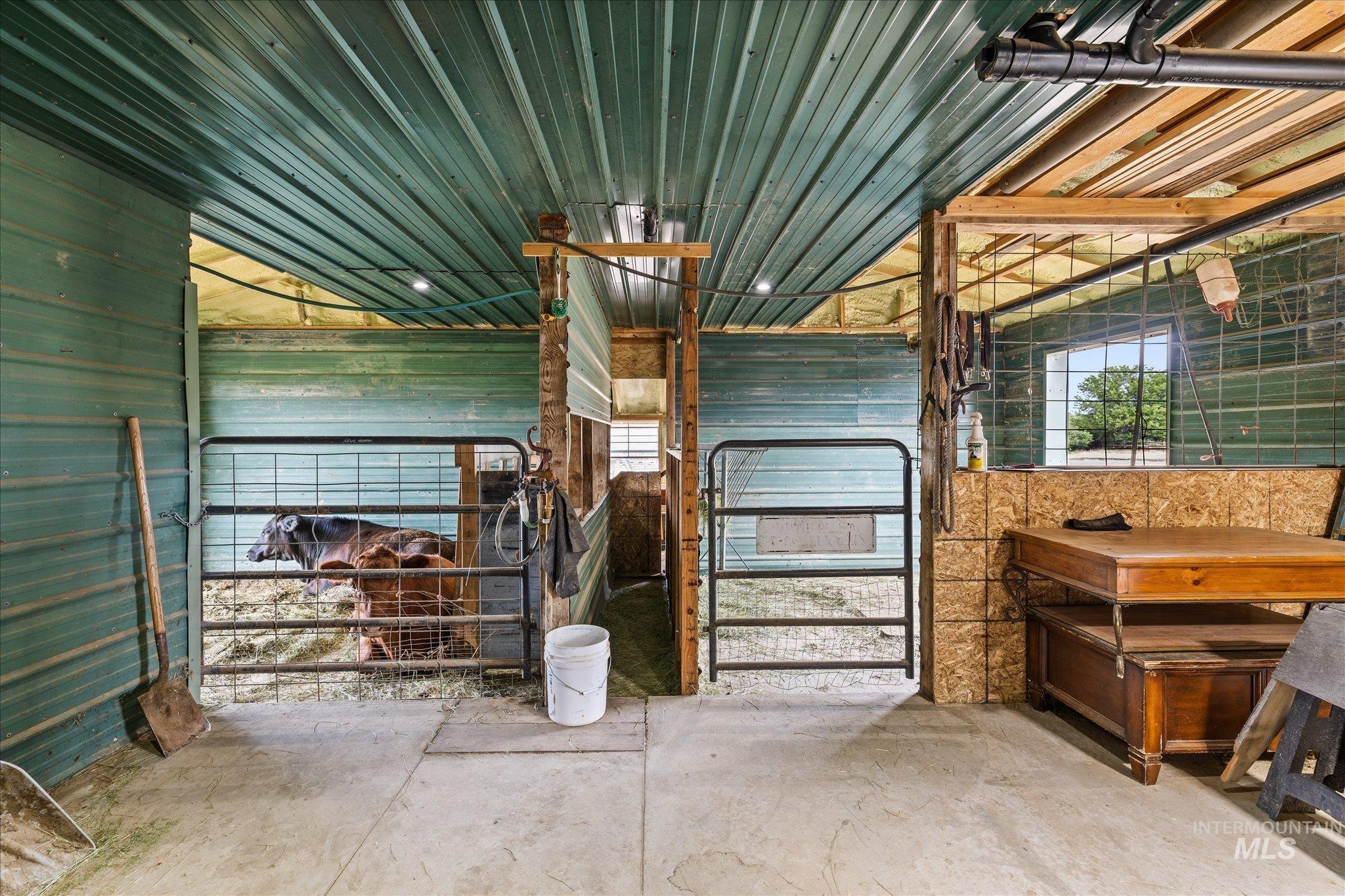 1140 Edgemont Road Emmett, ID 83617 - Photo 41 of 50 Interior barn structure featuring a corrugated green metal roof and walls, concrete flooring, and multiple gated stalls
