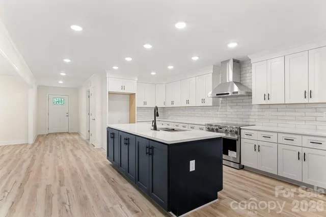 a kitchen with stainless steel appliances granite countertop a sink a stove a refrigerator and a oven with wooden floor