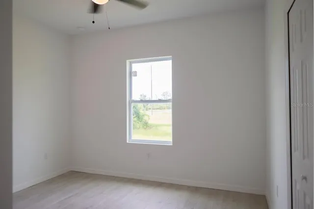 a view of a big room with wooden floor and windows