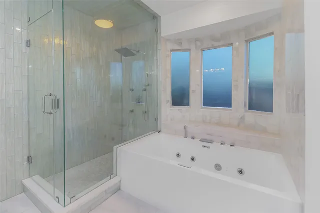 a bathroom with a tub sink shower and mirror