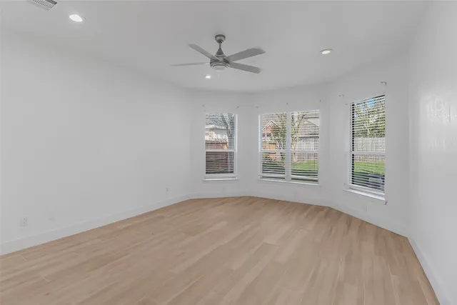 an empty room with windows and chandelier fan
