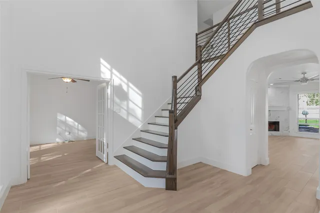 a kitchen with stainless steel appliances granite countertop a refrigerator a sink dishwasher a stove and white cabinets with wooden floor