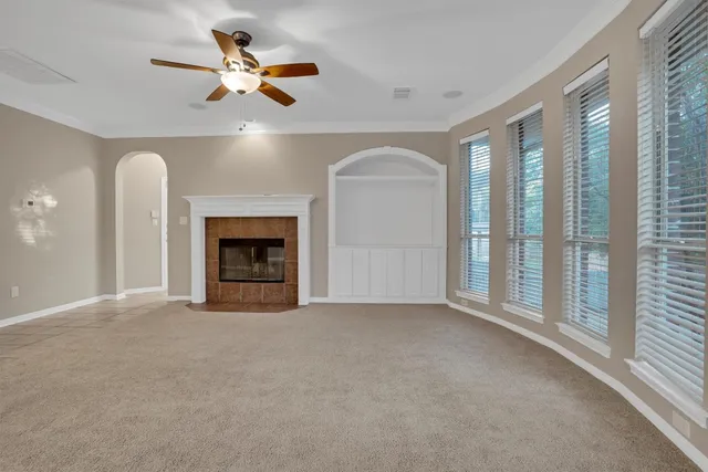 an empty room with ceiling fan and windows