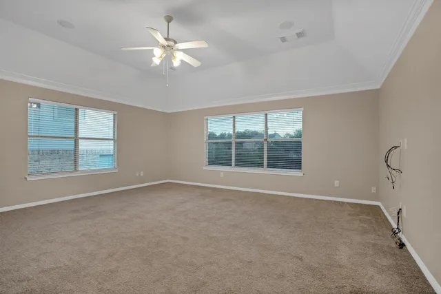 an empty room with windows and chandelier fan