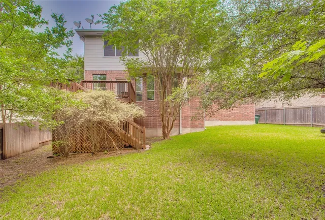 a view of a backyard with plants and large trees