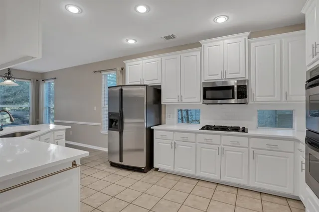 a kitchen with white cabinets and stainless steel appliances