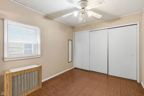 an empty room with wooden floor chandelier fan and windows
